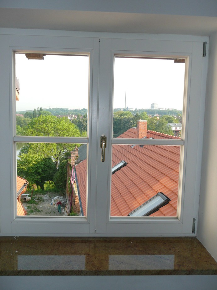 Bílé dřevěné okno s výhledem na okolní zahradu